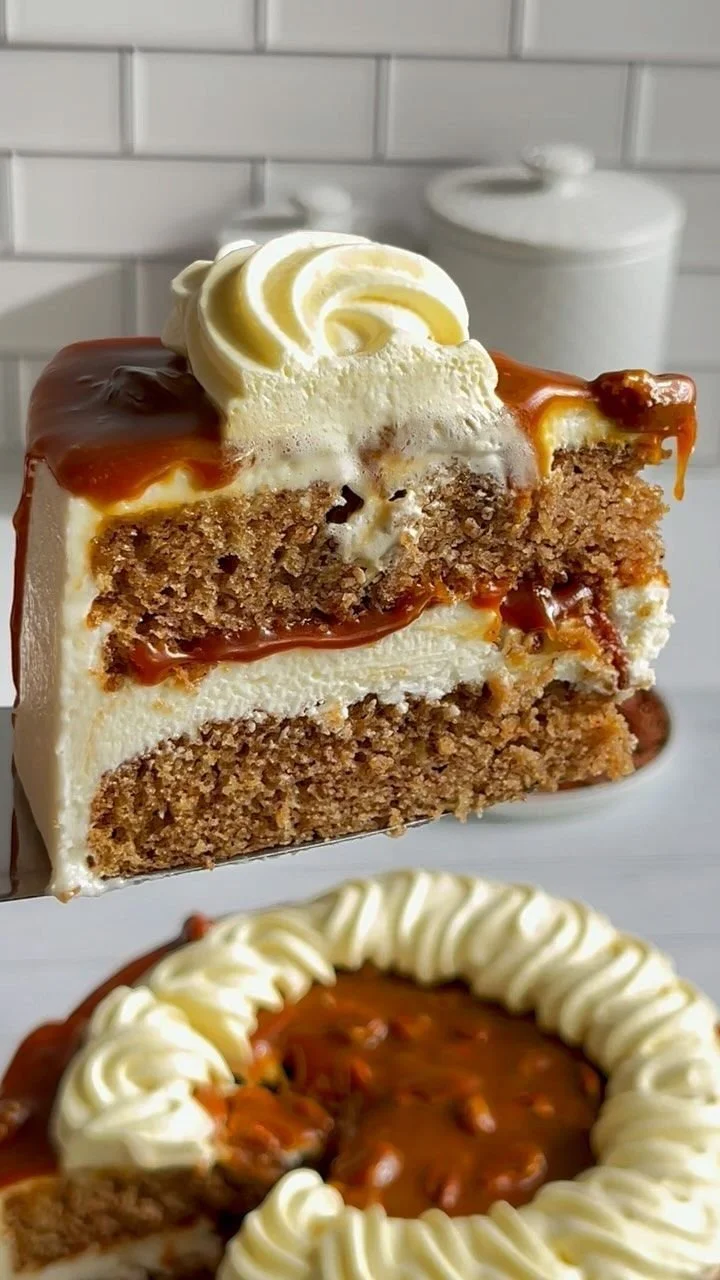 Caramel spice cake with cream cheese frosting and toasted pecans on a serving plate