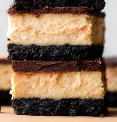 Decadent Chocolate Peanut Butter Cheesecake Bars topped with chocolate drizzle.